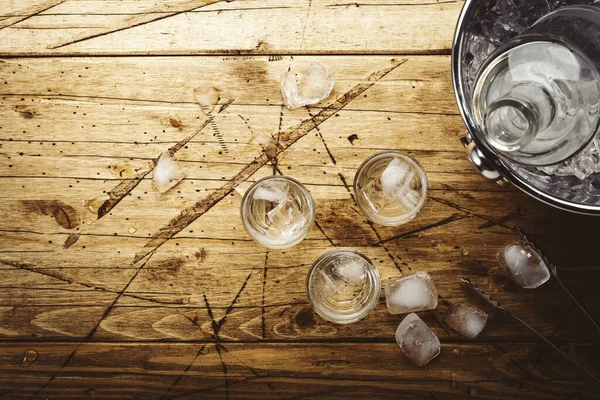 木製のテーブルの上にショットグラスでロシアのウォッカ ミスガラスで強いアルコール飲料をアイス トップビュー 負の空間 — ストック写真