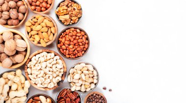 Fındıklar kaselerde. Badem, fındık, ceviz ve diğerleri. Sağlıklı yiyecek karışımı beyaz masa, üst görünüm, kopyalama alanı