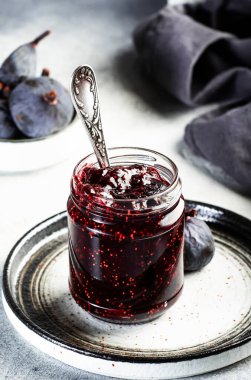 Cam kavanozda incir ziyafeti. Gri mutfak masasında taze meyve, negatif alan.