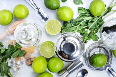 Mojito kokteyli yapmak. Nane, kireç, buz, beyaz rom, kamış şekeri, malzemeler ve bar aletleri. Üst manzara, beyaz arkaplan. Düz yatıyordu