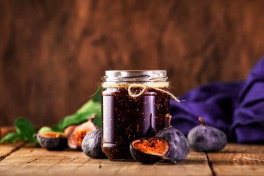 Cam kavanozda incir ziyafeti. Ahşap mutfak masasında taze meyve, negatif alan.