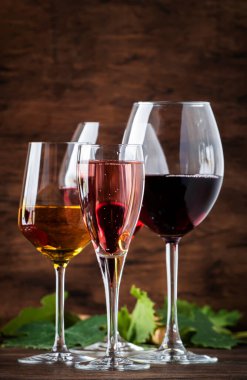 Wine tasting. Red, white, rose and champagne - still and sparkling wines sin glasses on vintage wooden table background clipart