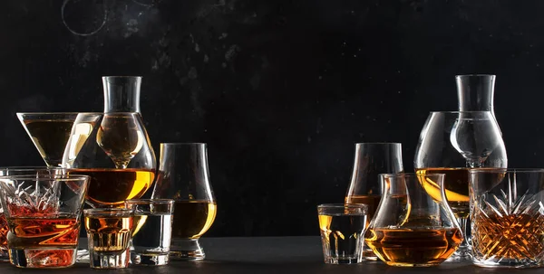 強いアルコール飲料 ハードリキュール スピリッツ グラスにセットされた蒸留所 コニャック スコッチ ウイスキーなど ブラックバーカウンターの背景 — ストック写真
