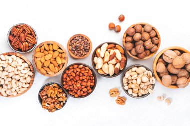 Fındıklar kaselerde. Badem, fındık, ceviz ve diğerleri. Sağlıklı yiyecek karışımı beyaz masa, üst görünüm, kopyalama alanı
