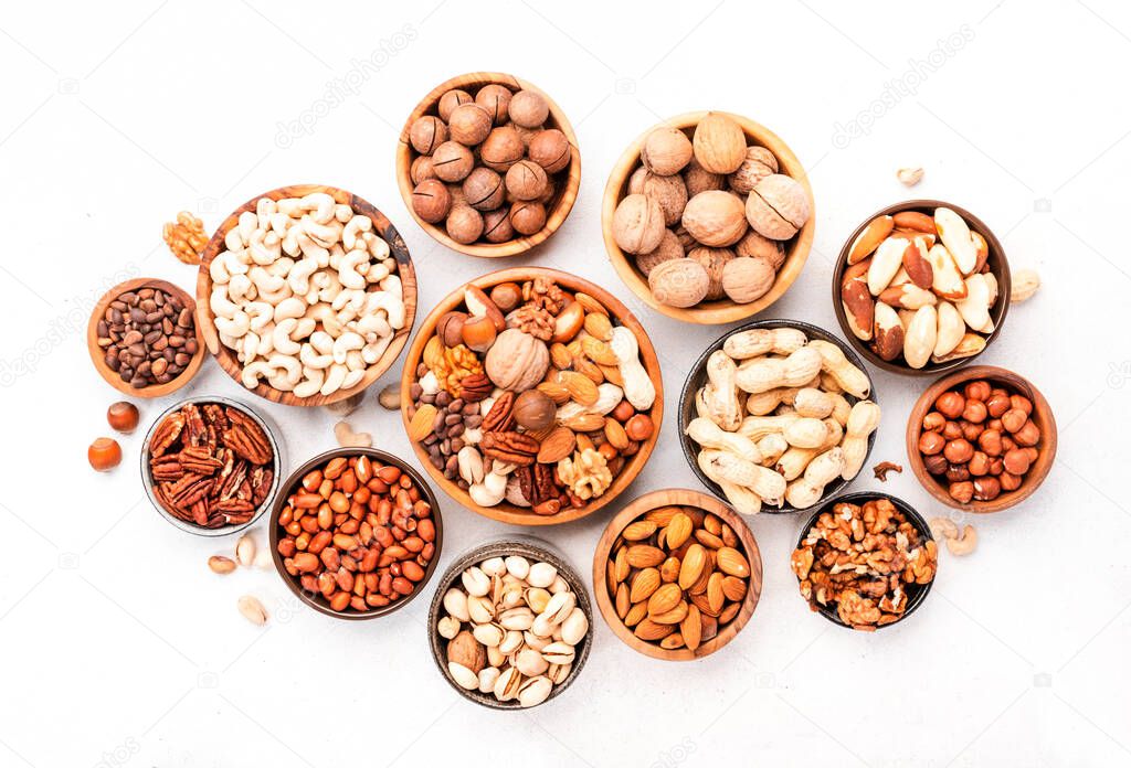 Nuts in bowls. Almonds, hazelnuts, walnuts and other. Healthy food snack mix on white table, top view, copy space