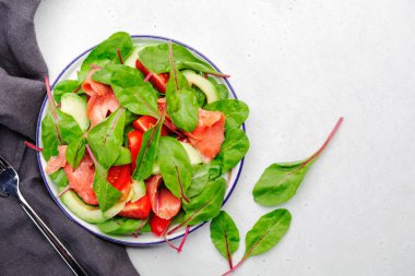 Somon avokado salatası, pancar yaprağı, radicchio, domates, keto için limon ve zeytinyağı sosu ve düşük kart diyeti. Gri arkaplan, üst görünüm