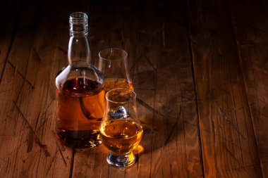 Özel bardaklarda viski, eski ahşap arka planda negatif alan.