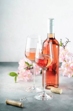 Gri masada şarap kadehi ve şişe ve pembe çiçekler. Rosado, rosato veya kırmızı şarap tatma. 