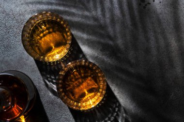 Amerikan viskisi bardakta ve şişede, siyah arka plan gölge desenli ve negatif alan