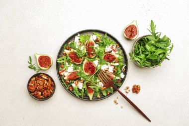Yumuşak keçi peynirli incir salatası, ceviz, roka ve reçel soslu beyaz arka plan, üst manzara, kopyalama alanı.