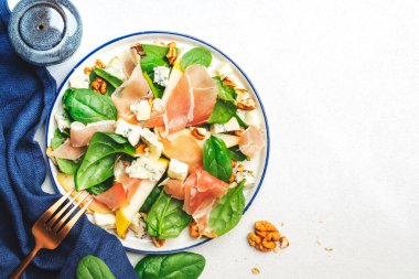 Prosciutto 'lu armut salatası, mavi peynir, ıspanak, beyaz arka planda ceviz, üst manzara, kopyalama alanı