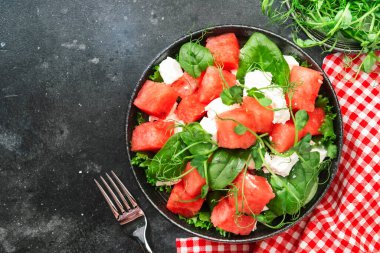Yumuşak keçi peynirli karpuz salatası kasesi, gri arka planda ıspanak ve bezelye filizi, üst manzara, kopyalama alanı