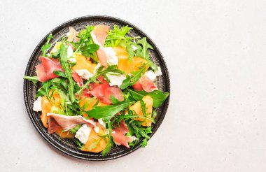 Kavun salatası kavun, prosciutto, keçi peyniri ve roka beyaz arka planda, üst manzara, kopyalama alanı