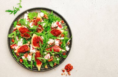 Yumuşak keçi peynirli incir salatası, ceviz, roka ve reçel soslu beyaz arka plan, üst manzara, kopyalama alanı.