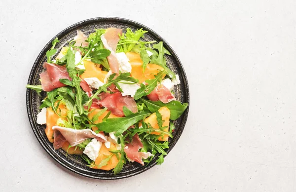 Meloensalade Met Meloen Prosciutto Geitenkaas Arugula Witte Achtergrond Bovenaanzicht Kopieerruimte — Stockfoto