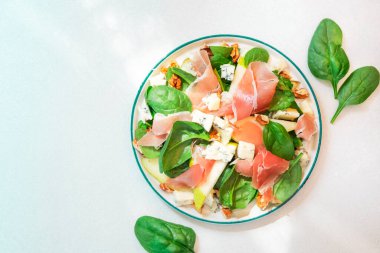 Prosciutto 'lu armut salatası, mavi peynir, ıspanak, beyaz arka planda ceviz, üst manzara, kopyalama alanı