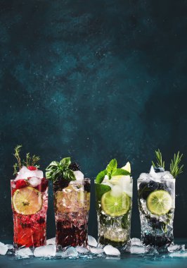 Kokteyl içecekler. Klasik alkolik uzun içkisi ya da mavi arka planda böğürtlenli, limonlu, otlu ve buzlu moktail viski.