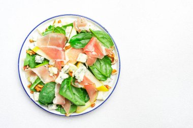 Prosciutto 'lu armut salatası, mavi peynir, ıspanak, beyaz arka planda ceviz, üst manzara, kopyalama alanı