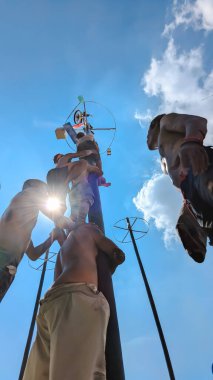 Kuzey Cakarta, Endonezya. 17 Ağustos 2025. Düşük açı. Takımdaki gençler yağlı bir direğe tırmanmak ve ödül kazanmak için yarışıyorlar. Bu popüler Endonezya Bağımsızlık Günü etkinliği birlik ve azmi simgeliyor..