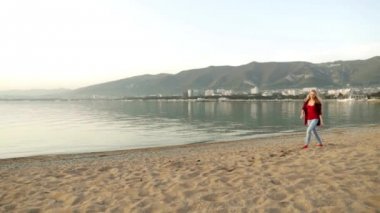 Sahilde yürüyen bir kız. Kız ve deniz. Denizde eğlenen kız. Neşe, kaygısız, eğlence. sevinçiçin atlama. Kumda yürüyor. Akşam denizde. Kum plajı. Sahil. mutluluk girdabı. 