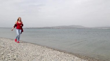 Sahilde yürüyen bir kız. Kız ve deniz. Neşe, kaygısız, eğlence. kayalık plaj. Sakin deniz. Sahil. ıssız plaj. denizin tadını çıkarın. yalnızlığın tadını çıkarın. denize taş atmak. Çakıl.