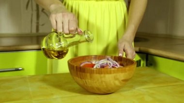 Woman pours salad oil. Female hands watering vegetables oil. Wooden salad bowl. Fresh vegetables. Olive oil. Oilcan. Tomatoes, cucumbers, onion. bamboo bowl. In the kitchen. house-proud woman.