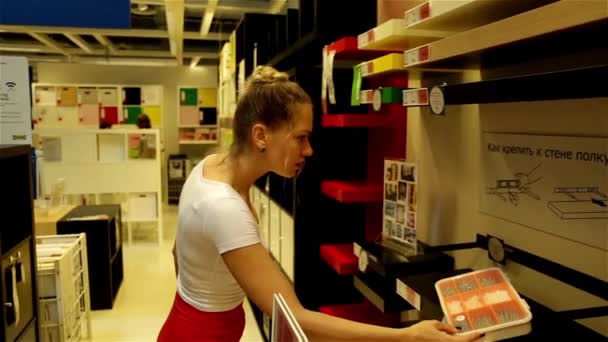 IKEA. Russie, Krasnodar 28 / 05 / 2016. Femme dans un supermarché. La fille du magasin. Acheteur. Le commerce. Centre commercial. Choisissez une bibliothèque. Achetez une étagère. Magasin de meubles — Video