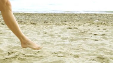 Kadın ayaklar kumun üzerinde. Kum, deniz, güzel bacaklar. Kız Sahilde yürüyüş. 