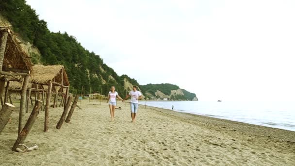 Coppia amorevole che corre lungo la spiaggia. Sposi che corrono lungo il mare, al rallentatore. Luna di miele, romanticismo, appena sposato . — Video Stock