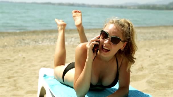 Femme allongée sur une chaise longue et parlant au téléphone. Fille en maillot de bain parlant au téléphone sur le fond de la mer. Femme au téléphone, soleil sur la plage, détente au bord de la mer . — Video