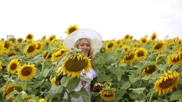 Kvinna bland solrosor. Flicka i ett fält av solrosor. Kvinnan ler i ett fält av solrosor. Sommar, natur, soligt väder. — Stockvideo