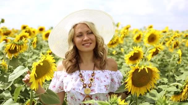 Mädchen in einem Feld von Sonnenblumen. Frau, die zwischen Sonnenblumen geht. Frau lächelt und geht in einem Feld von Sonnenblumen. Sommer, Natur, sonniges Wetter. — Stockvideo