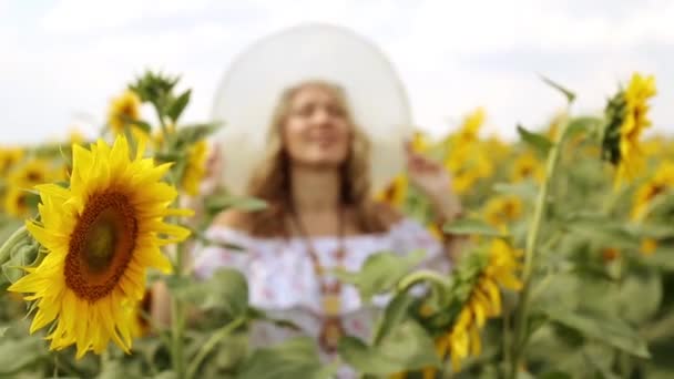 O femeie zâmbind într-un câmp de floarea-soarelui. Femeia printre floarea-soarelui. Fata într-un câmp de floarea soarelui. Vară, natură, vreme însorită . — Videoclip de stoc