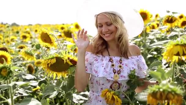 Donna che cammina tra i girasoli. Ragazza in un campo di girasoli. Donna che sorride e cammina in un campo di girasoli. Estate, natura, tempo soleggiato . — Video Stock