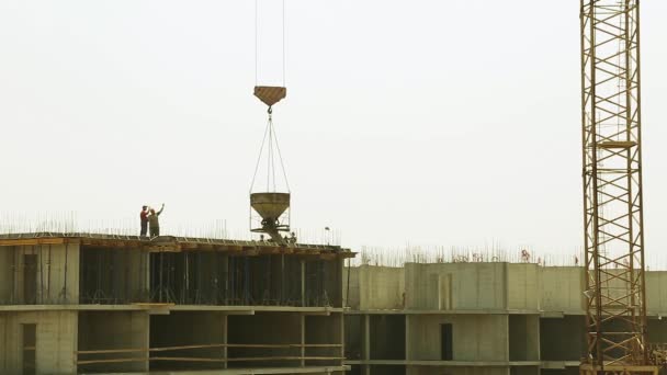 La gru edile solleva il carico. Casa in costruzione. Costruzione di un edificio a più piani. I costruttori riempiono casa cornice. Costruzione di edifici multipiano . — Video Stock