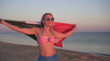 Deniz kıyısında Meksika bayrağı taşıyan bikinili genç seksi kadın.