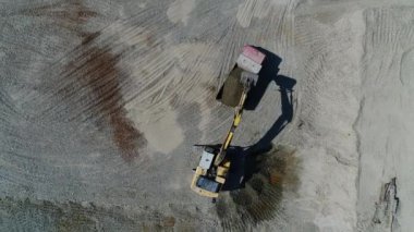 Hava görüntüsü: Bir kazıcı bir kamyona çakıl döküyor. Taş ocağı, madencilik, endüstriyel üretim