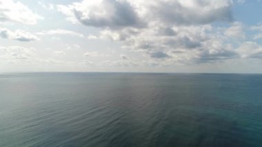 Hava: Bulutlu bir gökyüzünün arka planına karşı denizin yüksekliğinden bir manzara