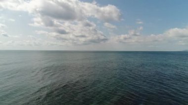 Güzel deniz arka planı, durgun mavi okyanus ve beyaz alçak bulutlu gökyüzü