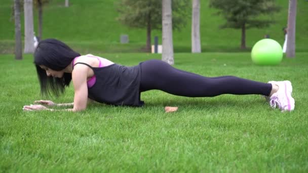 Sportieve sexy vrouw doen plank oefening in het park buiten. Sportvrouw is bezig met fitness buiten. — Stockvideo