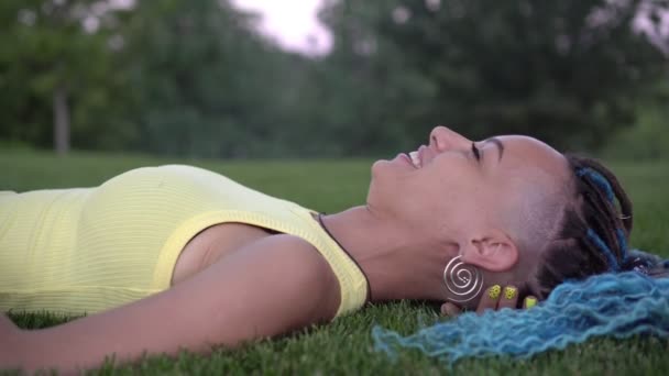 Jovem mulher atraente mente e descansa no parque na grama verde — Vídeo de Stock
