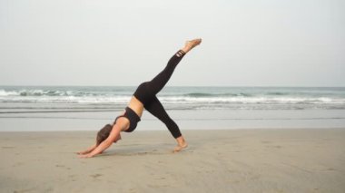 Genç kadın deniz kıyısında yoga yapıyor, vücut pozitifliği var.