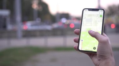 Bir adam elinde şehir haritası olan akıllı bir telefon tutuyor arka planda, yakın plan ekranda..