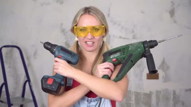 Забавная женщина держит строительные инструменты на фоне ремонта в доме — стоковое видео
