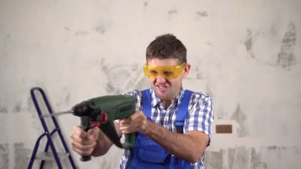 Trabajador de construcción loco con un perforador eléctrico. Funny trabajador de manitas alegre hace reparaciones — Vídeos de Stock