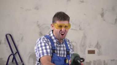 Komik çılgın inşaat işçisi elektrikli çekiç delicisiyle ateş ediyor.