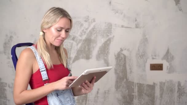 Жінка з планшетним комп'ютером на фоні ремонту в новому будинку . — стокове відео