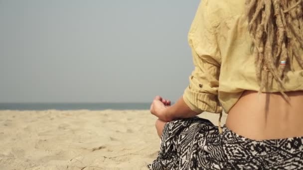 A hippie woman in hair dreadlocks meditates outdoors on the background of sea — Stockvideo