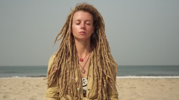 Young woman practices yoga and meditation in the lotus position on the sea coast — Stockvideo