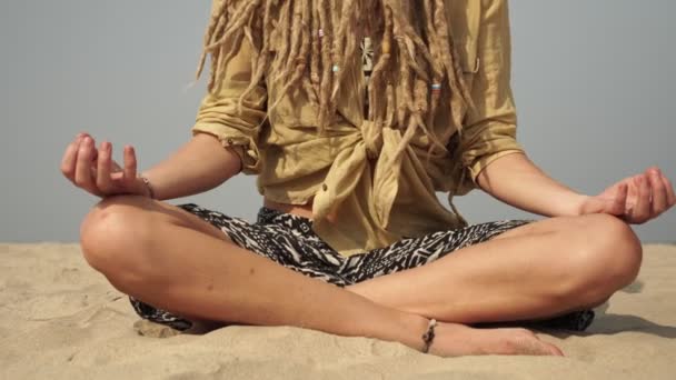 Женщина-хиппи практикует йогу и медитацию в позе лотоса на берегу моря — стоковое видео